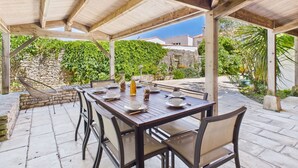 An outdoor patio with a wooden pergola, stone walls, and a view of the surrounding greenery and buildings. - 400 m from the beach, garden, house for 8 (Saint-Clément-des-Baleines)