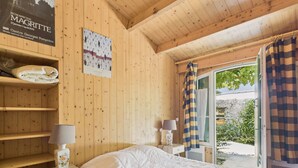 A wooden room with a bed, two bedside tables with lamps, a shelf with a folded blanket, and a poster on the wall. - 400 m from the beach, garden, house for 8 (Saint-Clément-des-Baleines)