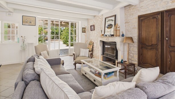 A spacious living room with a large sofa, a fireplace, and a stone wall. - 400 m from the beach, garden, house for 8 (Saint-Clément-des-Baleines)