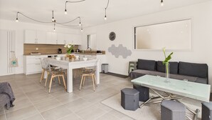 A modern kitchen with white cabinets, a wooden countertop, and a dining area with a glass table and chairs.