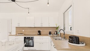 A modern kitchen with white cabinets, a wooden countertop, a built-in oven, a sink, and a toaster.