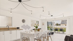 A modern kitchen with white cabinets, a wooden countertop, and a dining area with a glass table and chairs.
