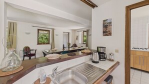 A compact kitchen with a sink, a coffee maker, and a dining area with chairs and a table.