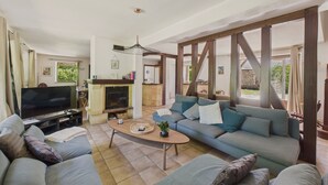 A spacious living room with a fireplace, a television, and a large sofa set.