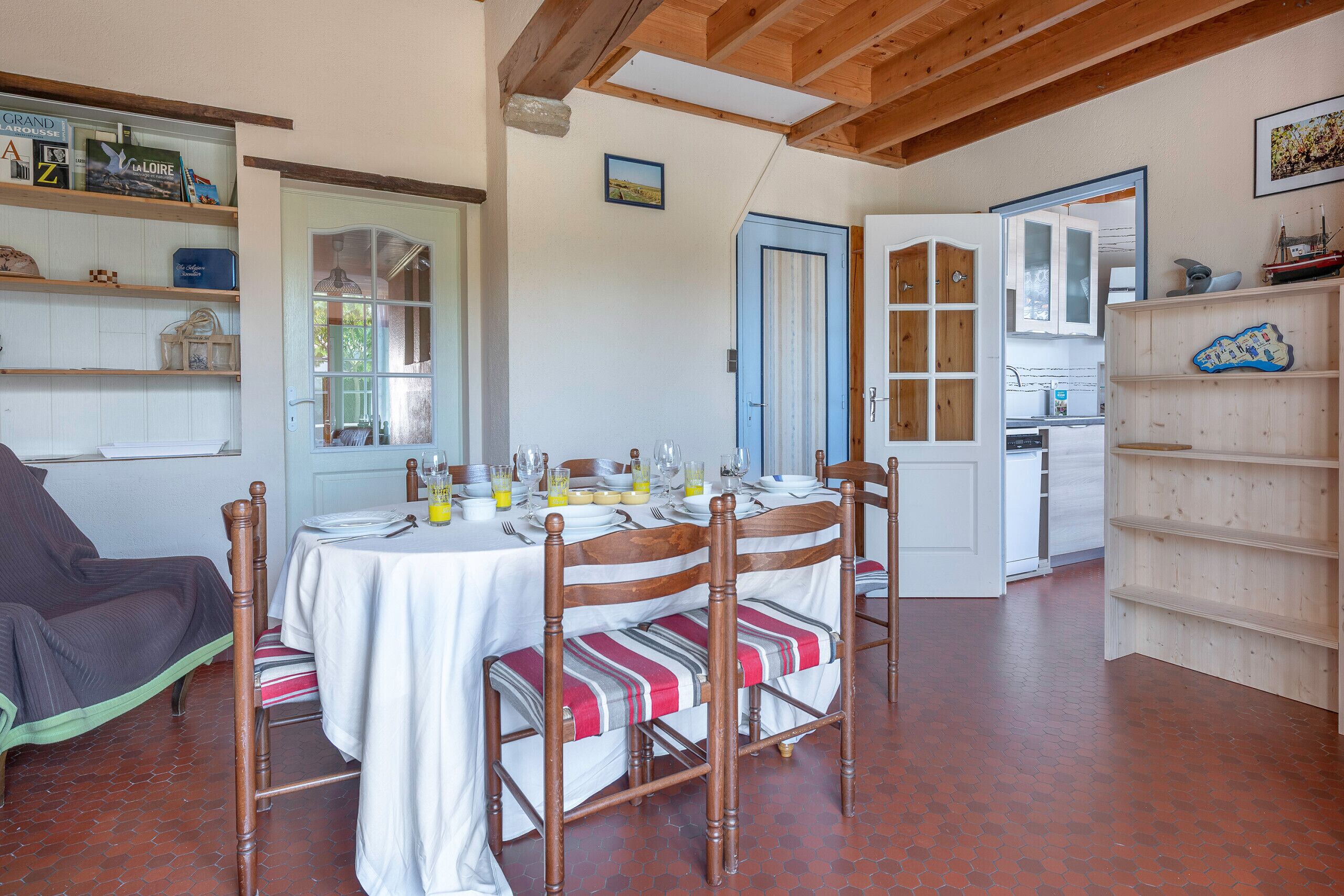 A dining area with a table set for four, wooden chairs, and a bookshelf to the right.