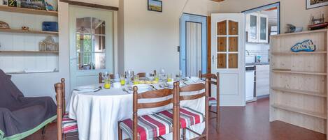 A dining area with a table set for four, wooden chairs, and a bookshelf to the right.