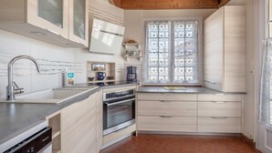 Een moderne keuken met een spoelbak van roestvrij staal, een inbouwoven en een raam met glas-in-lood.