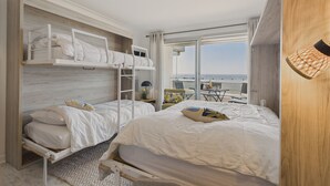 A modern hotel room with a balcony, two bunk beds, a small table, and a view of the sea. - Sea view,  studio for 4 just 40m from the beach (Les Sables-d´Olonne)
