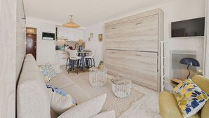 A modern living room with a sofa, coffee table, and a dining area with chairs and a table. - Sea view,  studio for 4 just 40m from the beach (Les Sables-d´Olonne)