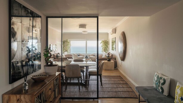A spacious living area with a view of the sea, a large abstract painting, and a modern dining setup.