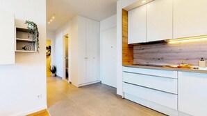 A modern kitchen with white cabinets, a wooden countertop, and a built-in oven. - Mika's 2-Bedroom Seaview Flat & Parking (Split)