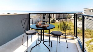 A balcony with a table and chairs, overlooking a cityscape and water. - Mika's 2-Bedroom Seaview Flat & Parking (Split)
