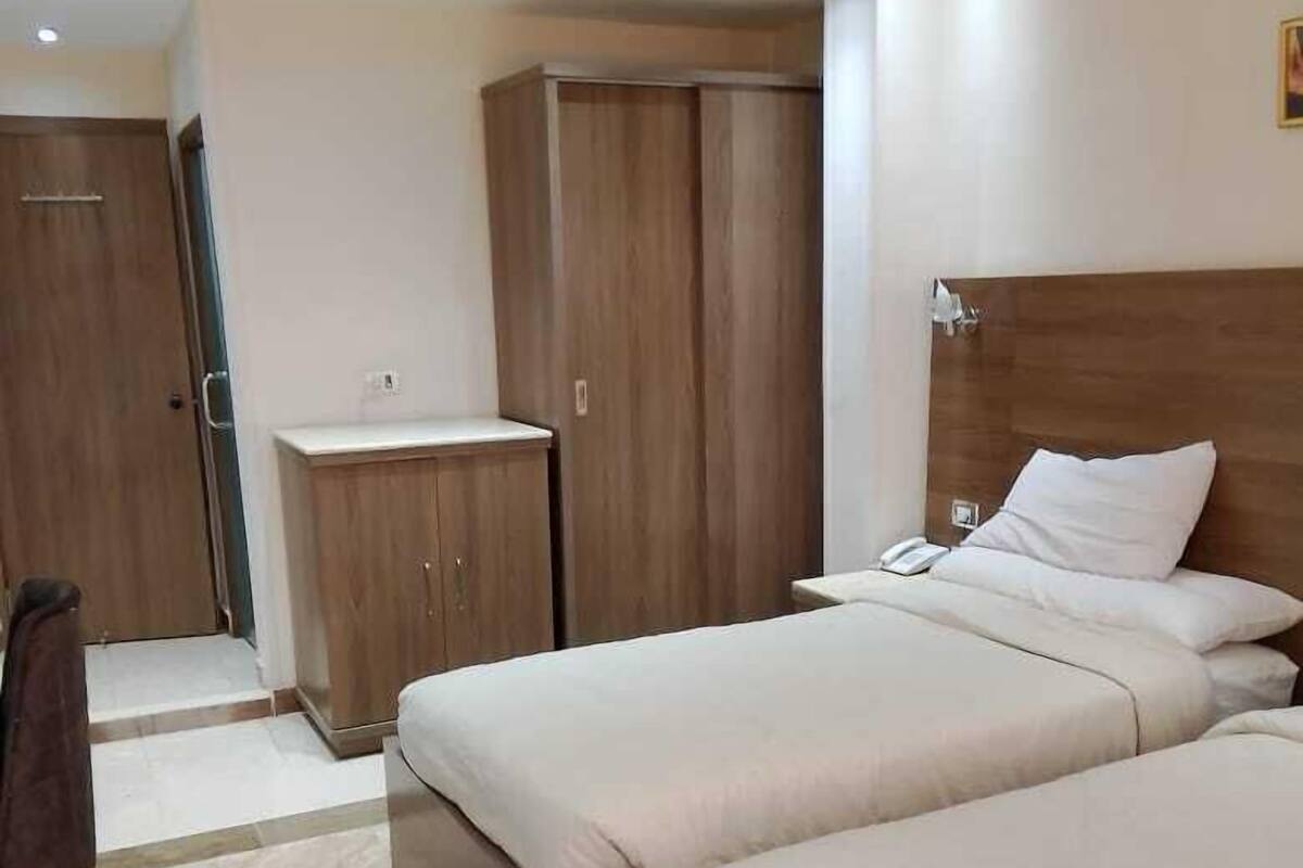 Hotellihuone, jossa on kaksi sänkyä, vaatekaappi ja työpöytä.