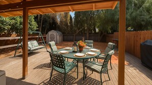 A covered patio with a round table set for four, surrounded by chairs. - Walk to Google 3BR Home Yard & Kitchen (Mountain View)