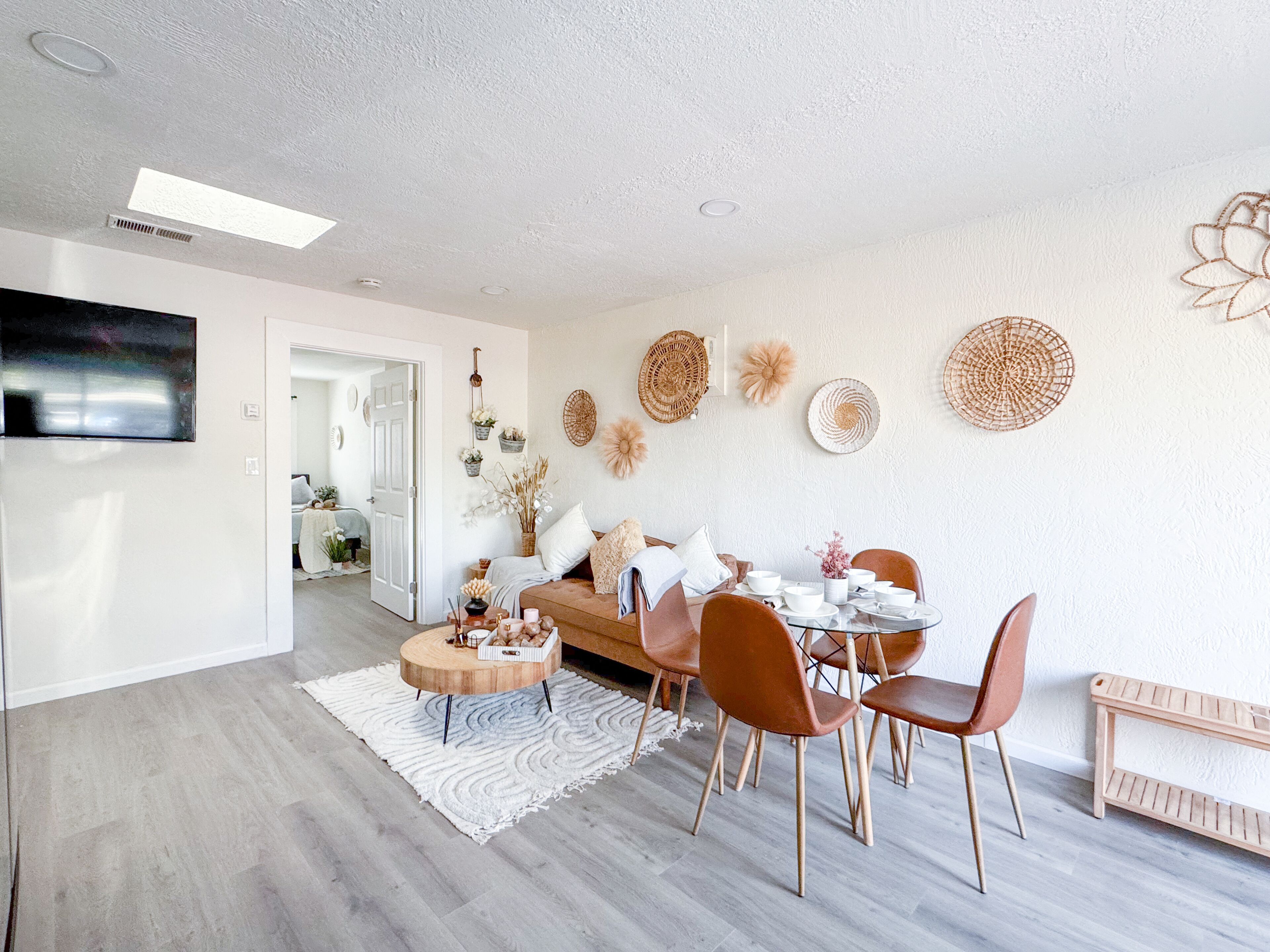 A modern living room with a dining area, featuring a sofa, chairs, a coffee table, and decorative wall art.