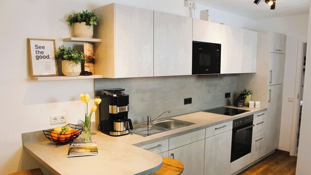 A modern kitchen with a built-in microwave, stainless steel sink, and wooden stools.