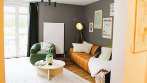 A modern living room with a green armchair, a leather sofa, and a round coffee table.