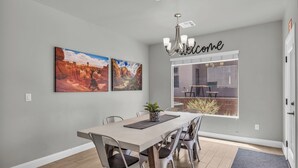 Un coin repas avec une table, des chaises et deux tableaux accrochés au mur.
