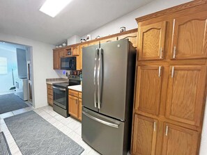 A modern kitchen with stainless steel appliances, wooden cabinets, and a tiled backsplash.