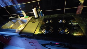 A kitchen with a sink, stove, and various kitchen items on the counter.