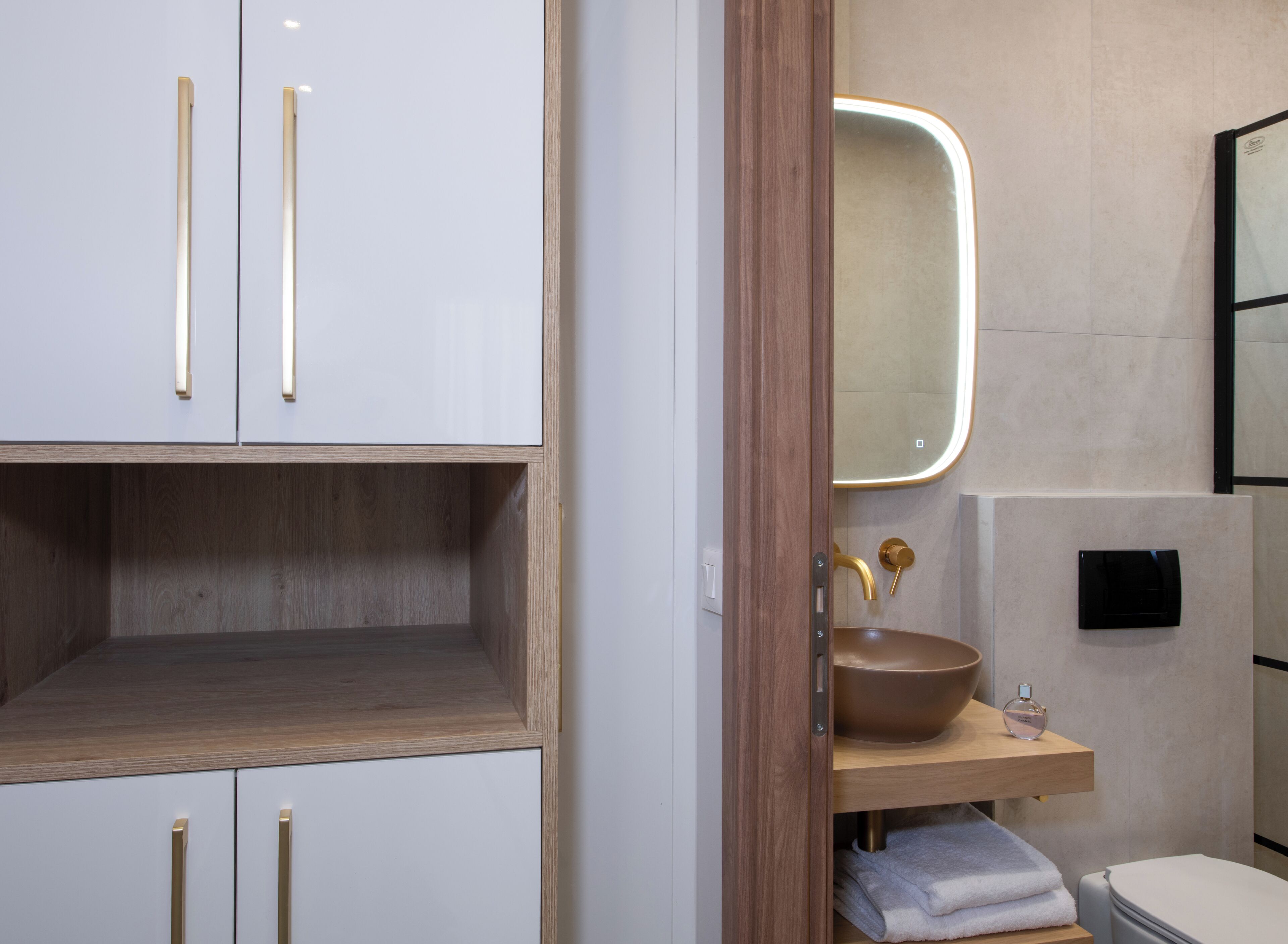 A modern bathroom with a wooden vanity, a large mirror, and a toilet.