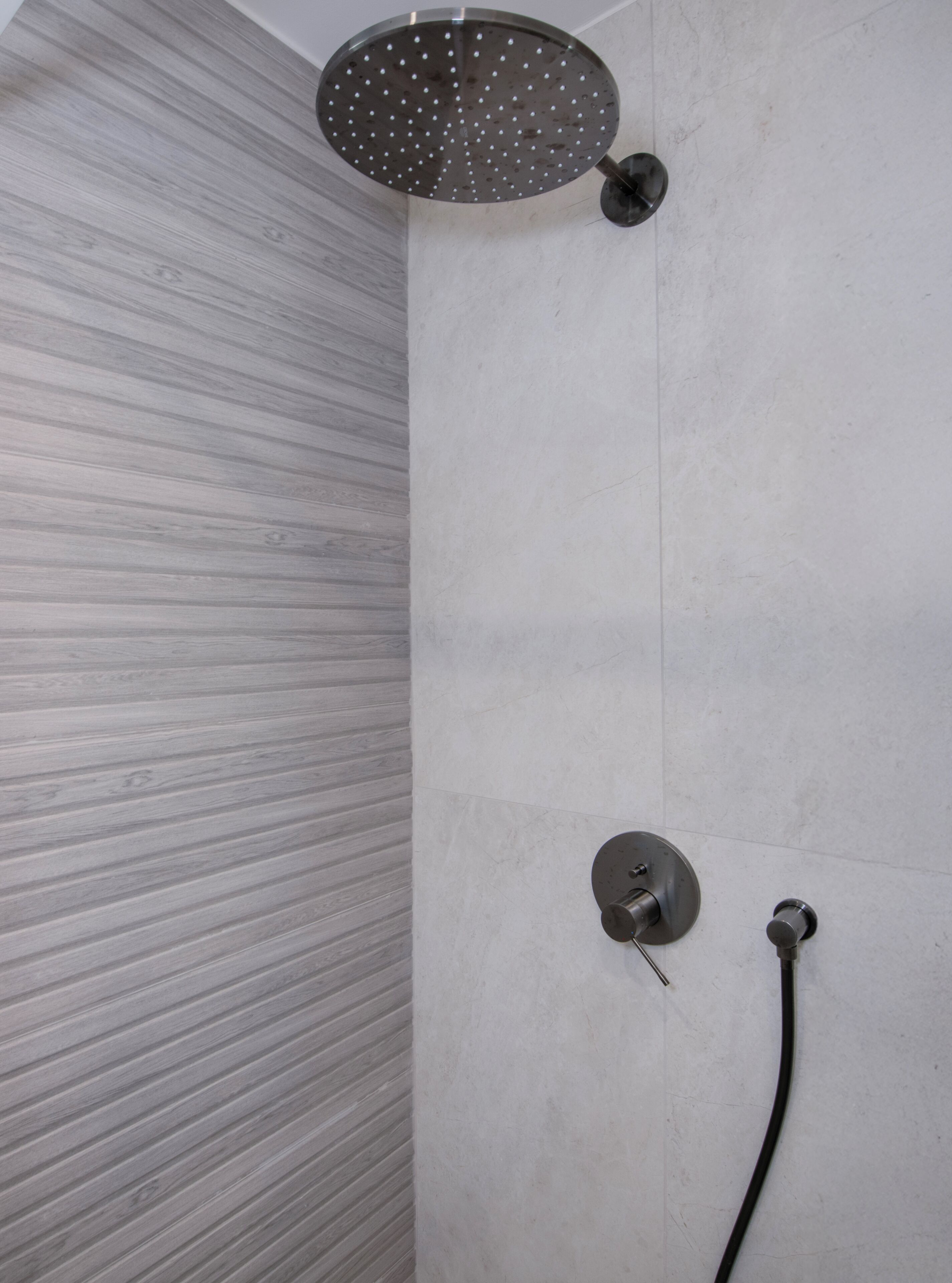 Eine Dusche mit Duschkopf und Handbrause, an einer Wand mit Holzoptik.