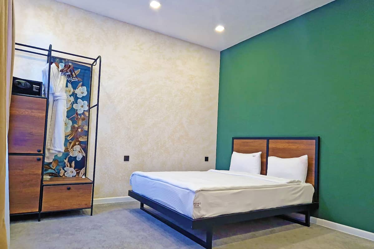 A bedroom with a bed, a wardrobe, and a green wall.