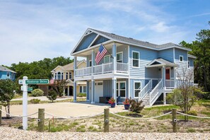 A two-story house with a balcony, a front porch, and a flag.