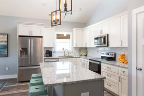 A modern kitchen with white cabinets, stainless steel appliances, and a granite countertop. - New Listing! Updated Beach Cottage&Community Perks (Corolla)