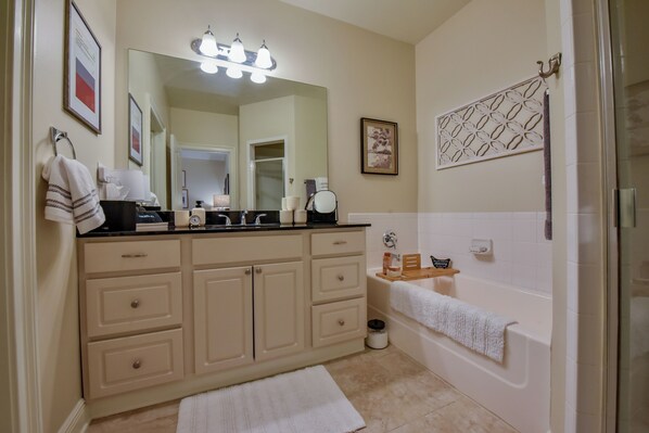 A bathroom with a large mirror, a sink, a bathtub, and a towel rack.