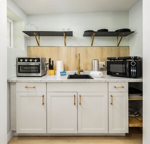 A compact kitchen with a built-in oven, microwave, and a wooden backsplash.