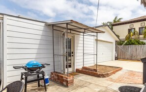 A patio with a grill, a covered area, and a garage door.