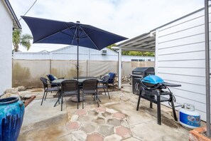A patio with a table and chairs, a grill, and a large umbrella. - Studio In Carlsbad Village (Carlsbad)