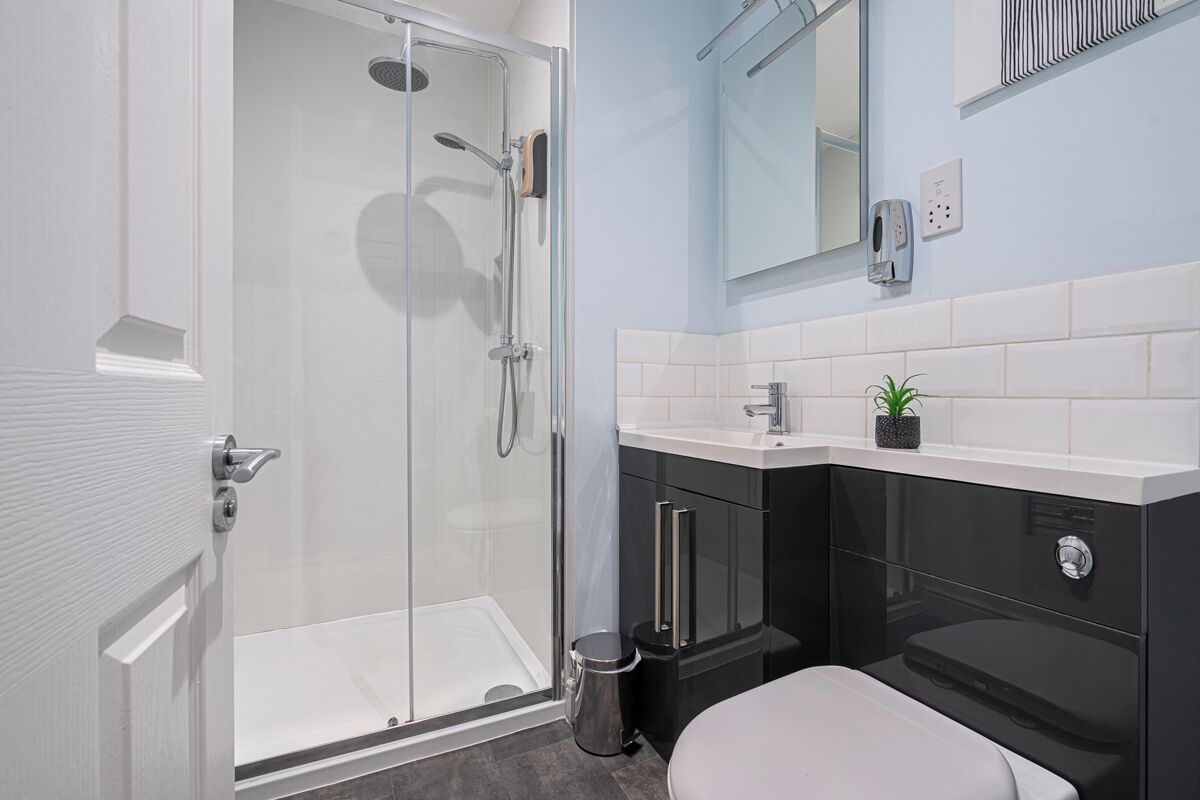 A modern bathroom with a glass shower enclosure, a sink with a mirror above, and a toilet.