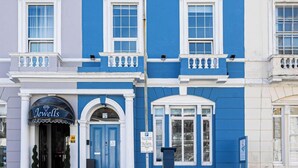 A two-story building with a blue and white facade, featuring a storefront with a sign that reads "Jewel's".