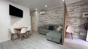Una sala moderna con comedor, un conjunto de sofás y un televisor de pantalla plana montado en la pared.