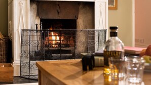 A fireplace with a metal screen, a bottle of Wild Turkey whiskey, and a glass on a wooden table. - The West Wing, Capheaton in Northumberland - sleeping 8 guests in 4 bedrooms (Capheaton)