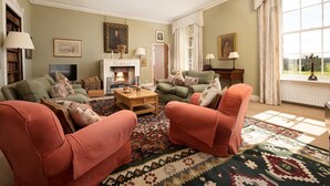A cozy living room with a fireplace, comfortable seating, and a view of the outdoors. - The West Wing, Capheaton in Northumberland - sleeping 8 guests in 4 bedrooms (Capheaton)