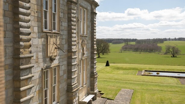 A stone building with a clock, large windows, and a view of a green field and trees. - The West Wing, Capheaton in Northumberland - sleeping 8 guests in 4 bedrooms (Capheaton)
