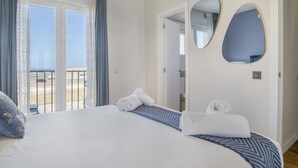 Habitación de hotel con cama, dos espejos, un balcón y una puerta que da al baño.