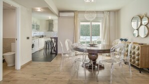 Una cocina moderna con comedor, sillas transparentes y una araña.