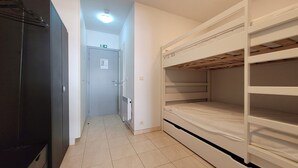 Una habitación con literas, kitchenette y una puerta con letrero de salida de emergencia.