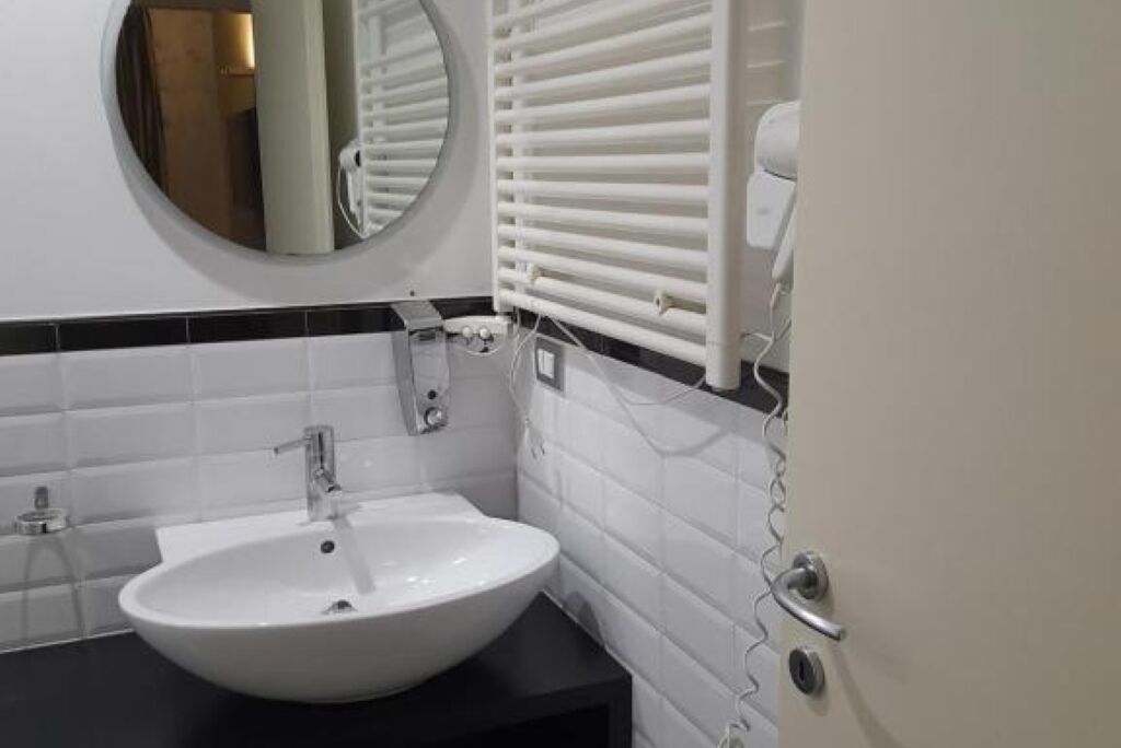 A bathroom with a white sink, a round mirror, and a towel rack.