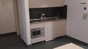 A compact kitchen with a microwave, sink, and a small countertop area. - FULL HOME. (Cosenza)