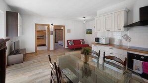 Una cocina moderna con gabinetes blancos, un microondas y un comedor con mesa de vidrio.