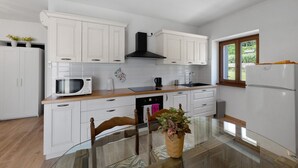 Una cocina moderna con armarios blancos, una campana extractora negra, un microondas, un fregadero y un refrigerador.