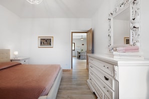 Un dormitorio con cama, cómoda, espejo y un cuadro en la pared.
