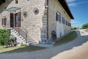 A stone building with a staircase, a wheel, and a bench.