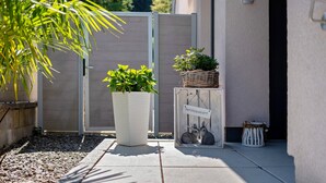 A small outdoor area with a potted plant, a wicker basket with greenery, and a decorative box with a rabbit figurine. - OsWALD Holiday Apartment (Ettenheim)