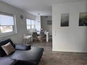 Un salon moderne avec un canapé, un coin repas et des œuvres d’art accrochées aux murs.